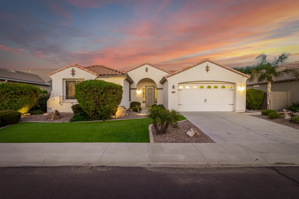 A Southwestern-style home’s inviting front door and landscaped garden lit by a colorful sunset sky. The tranquil atmosphere contrasts with the excitement of game day, suggesting the comfort and relaxation awaiting guests after attending local sports events.