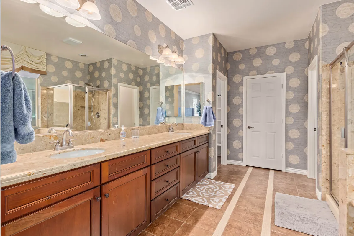 A cheerful bathroom with a double sink vanity, large mirrors, a shower area, and playful polka dot wallpaper. The design is both functional and inviting, with spa-inspired amenities perfect for post-adventure relaxation.